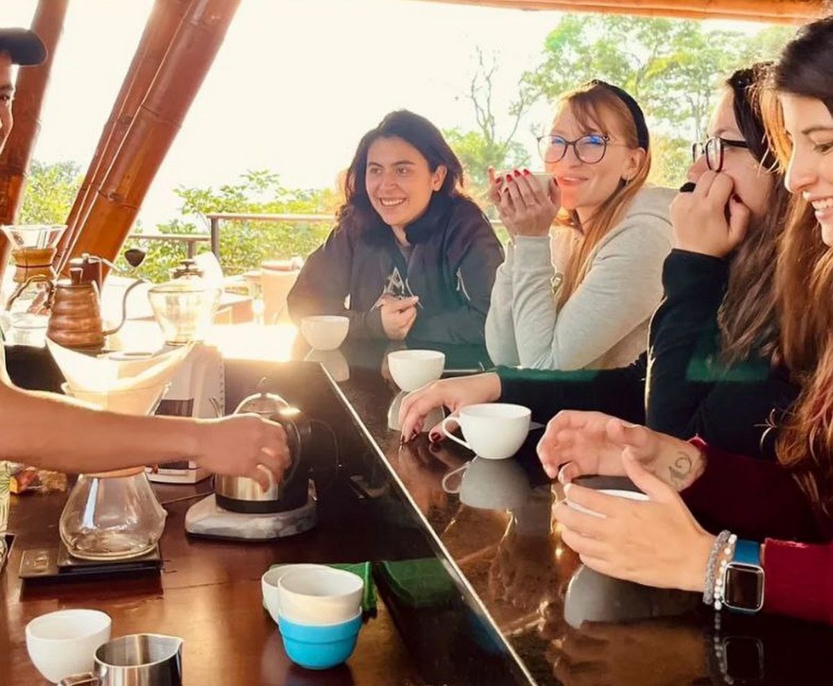 A group smiling over cups at the farm's coffee tasting bar